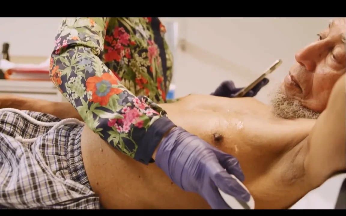 Vscan Air Erfahrungen in UK: Wie Handheld-Ultraschall Herzprobleme früh erkennt 5 Handheld-Ultraschallsonde auf der Brust eines liegenden Patienten während der Untersuchung